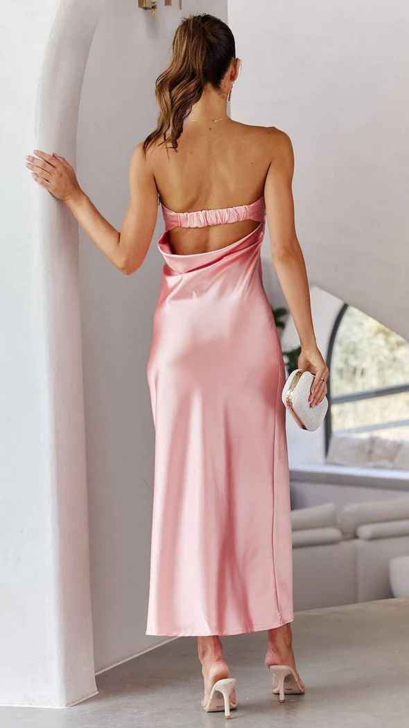 Satin strapless backless midi dress in soft pink with a side slit, worn by a model holding a clutch.