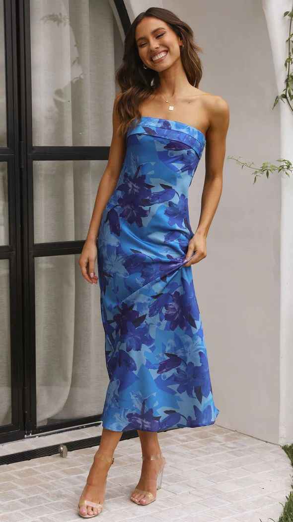 Satin strapless backless midi dress in blue with floral patterns, worn by a model standing outdoors.