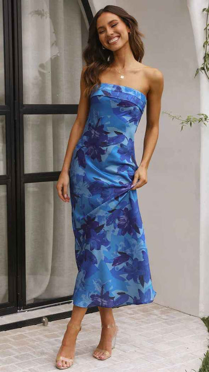 Satin strapless backless midi dress in blue with floral patterns, worn by a model standing outdoors.
