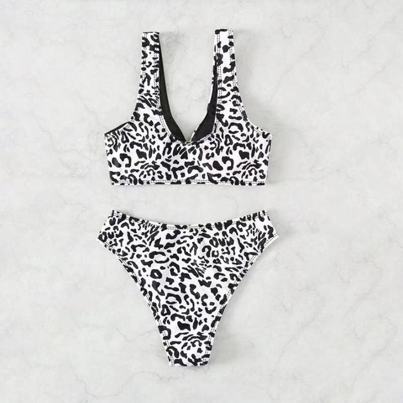 Split swimsuit featuring a leopard print design in black and white with contrasting solid black accents.