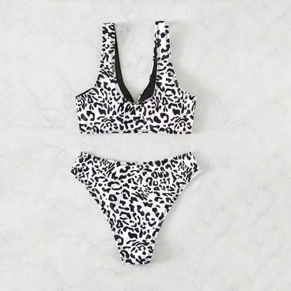 Split swimsuit featuring a leopard print design in black and white with contrasting solid black accents.