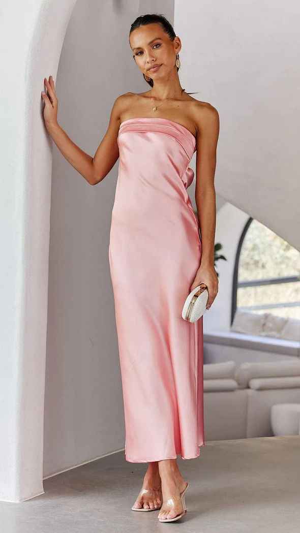 Satin strapless backless midi dress in soft pink, featuring a side slit, worn by a model with a clutch.