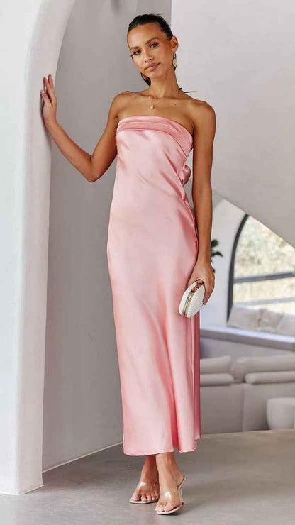 Satin strapless backless midi dress in soft pink, featuring a side slit, worn by a model with a clutch.
