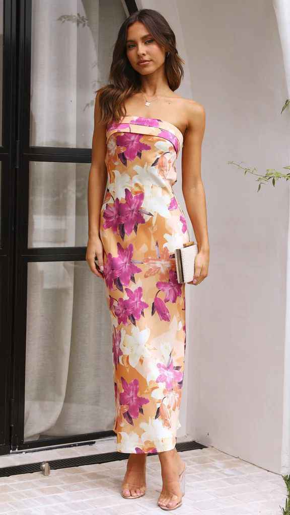 Satin strapless backless midi dress with floral print in peach, pink, and white, styled with a clutch and heels.