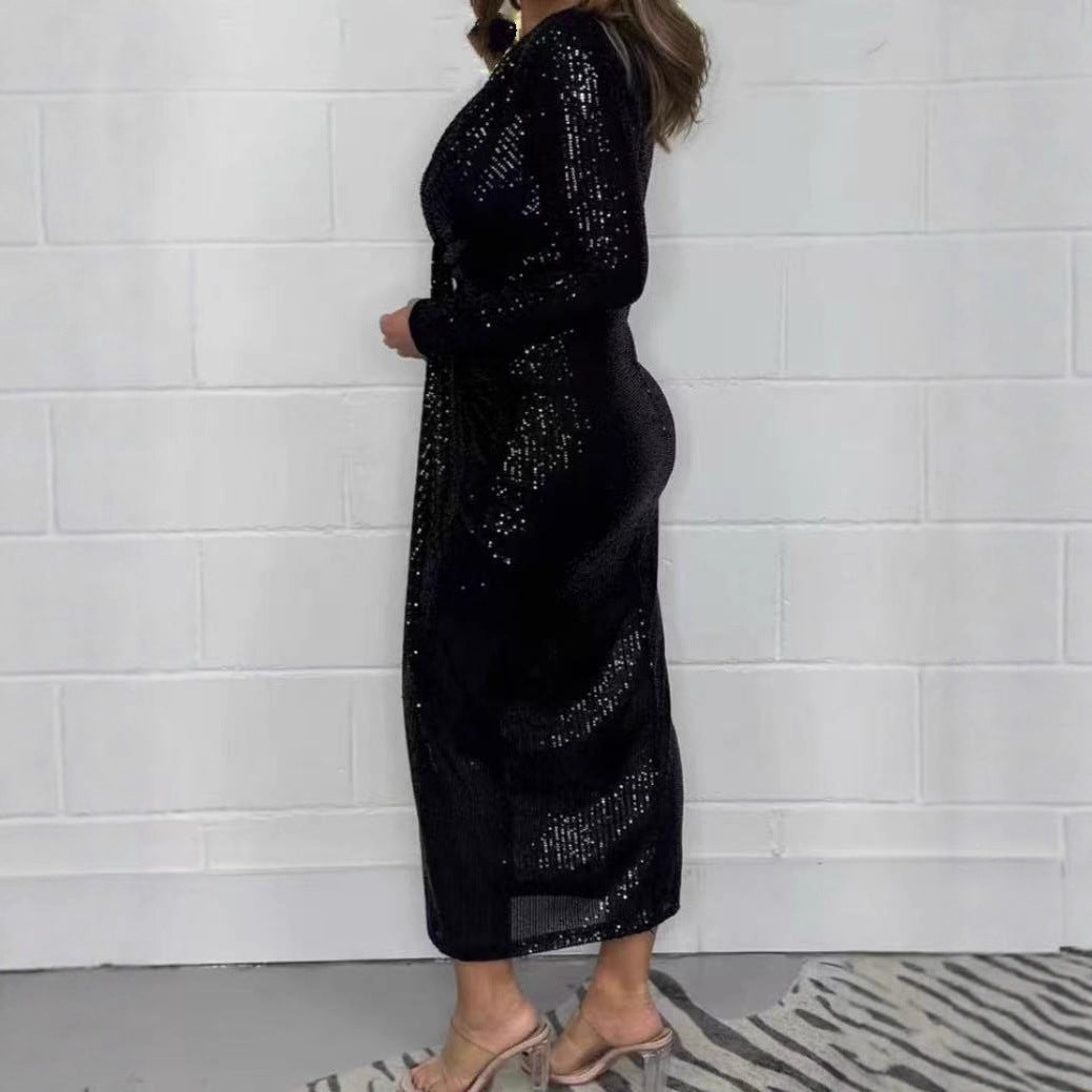 Black sequined low V-neck long sleeve cocktail dress displayed from the side against a white wall.