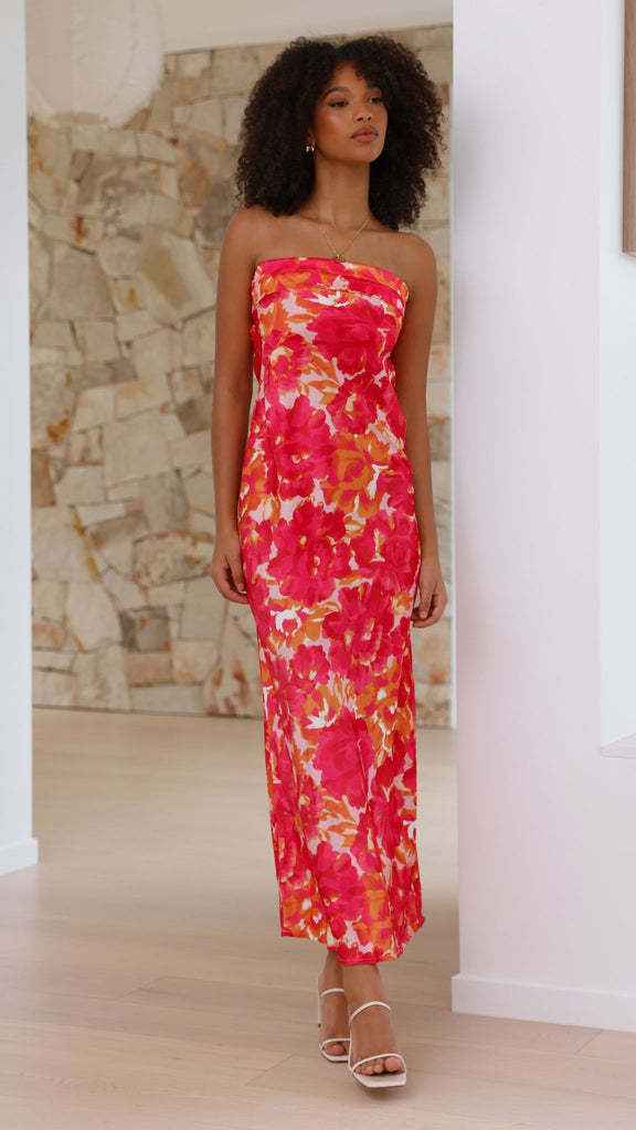 Satin strapless backless midi dress with a floral pattern in pink and orange, worn by a model in a bright interior.