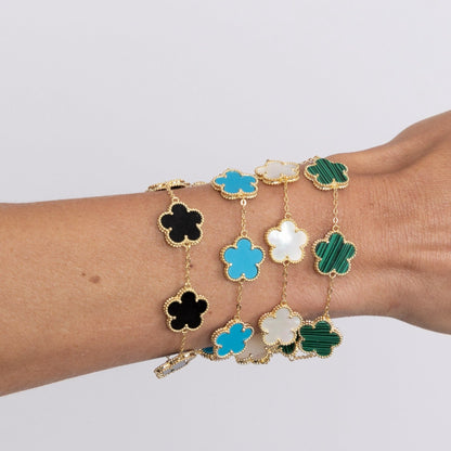 Bracelet with clover-shaped charms in various colors on a wrist against a light background