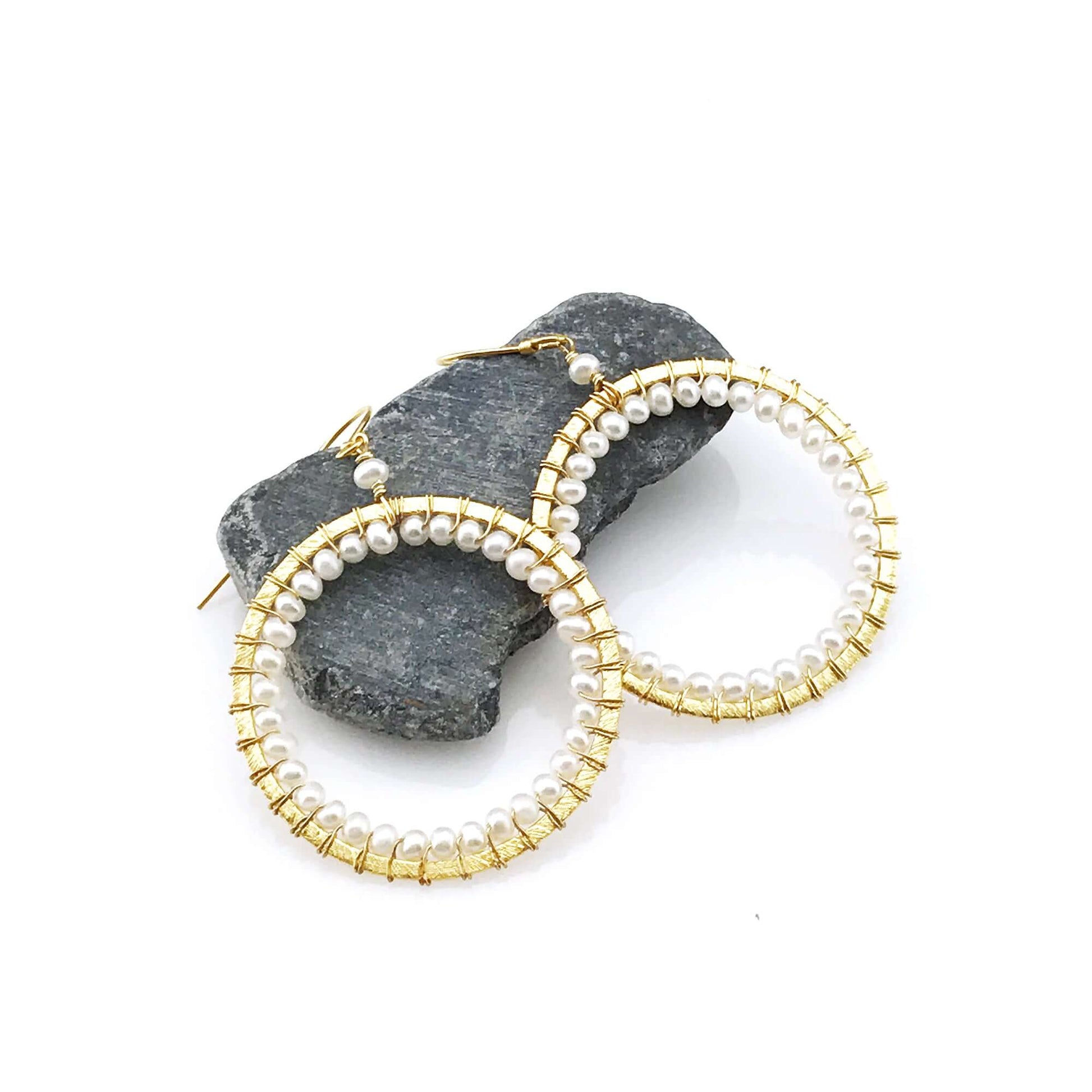 Gold hoop earrings with pearl beads on a white background