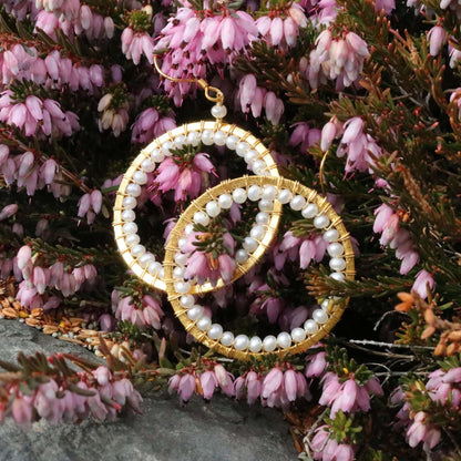 Gold and pearl hoop earrings on pink heather flowers