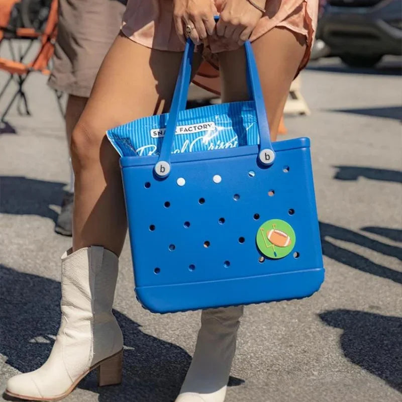 Person holding a blue tote bag with a brand logo on a street.