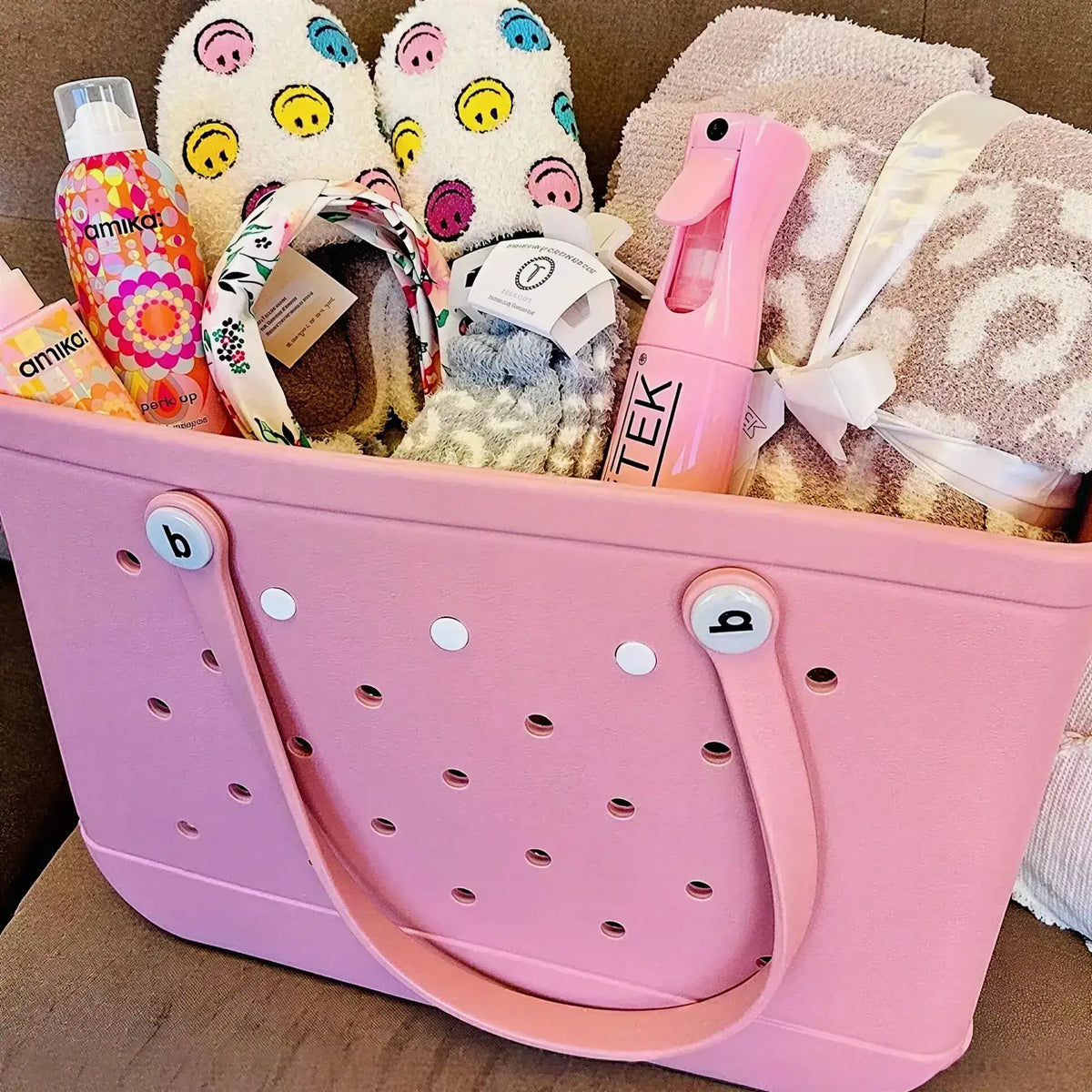 Pink tote bag filled with various items including a bottle, towel, and slippers.