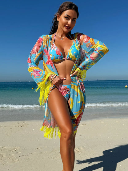 A woman on a beach wearing a blue three-piece swimsuit and cover-up with a pink and yellow seashell and starfish print.