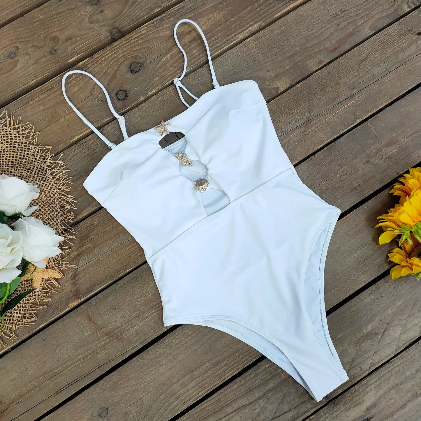 White swimsuit on a wooden surface with flowers