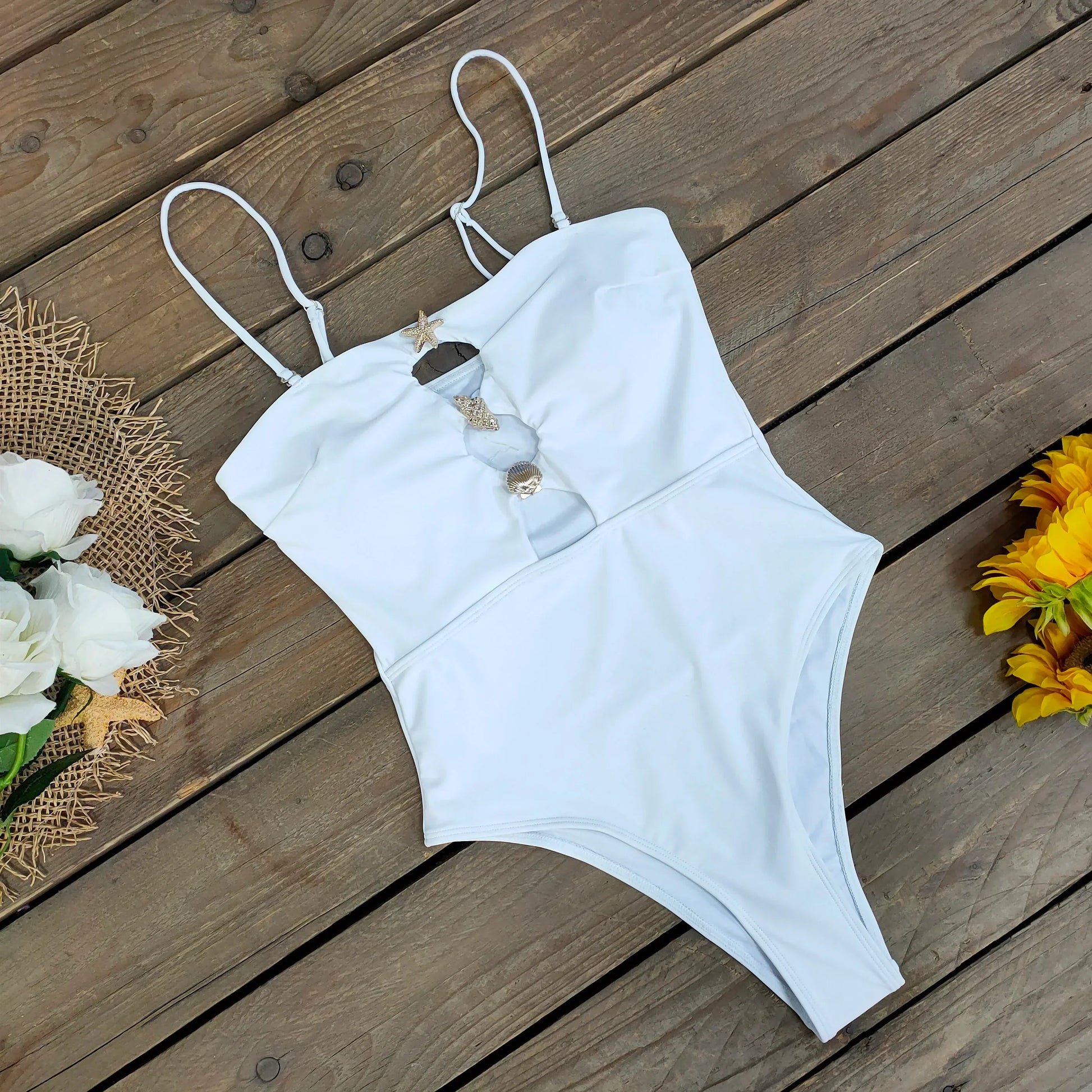 White swimsuit on a wooden surface with flowers