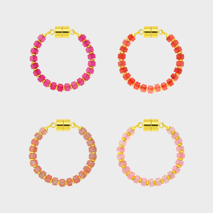 Four pairs of pink and red beaded hoop wine glass markers with gold accents on a light gray background.