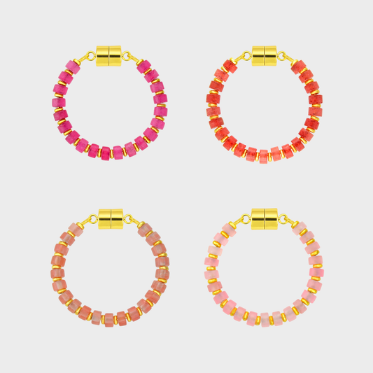 Four pairs of pink and red beaded hoop wine glass markers with gold accents on a light gray background.