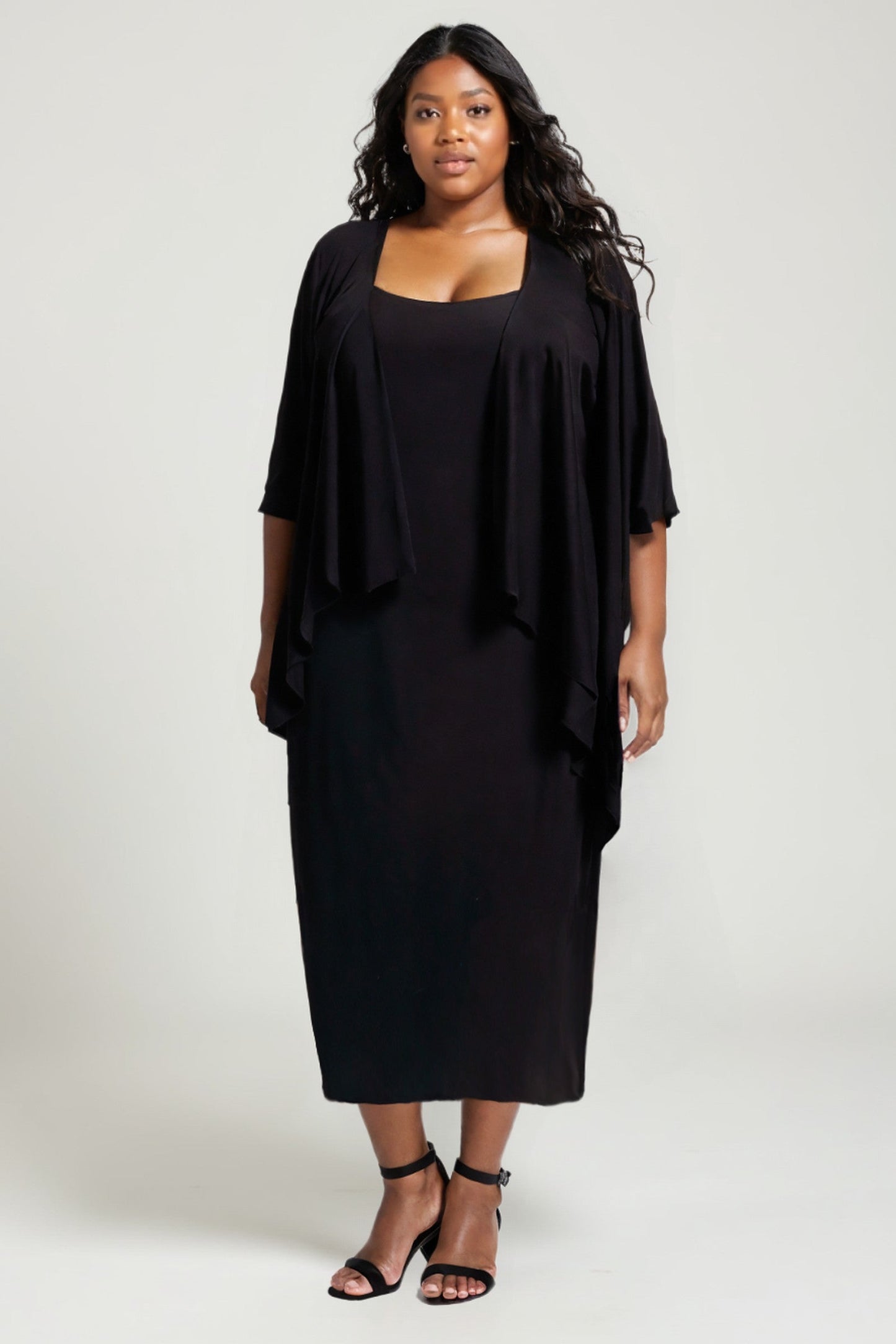 Woman wearing a black dress with a matching jacket on a white background