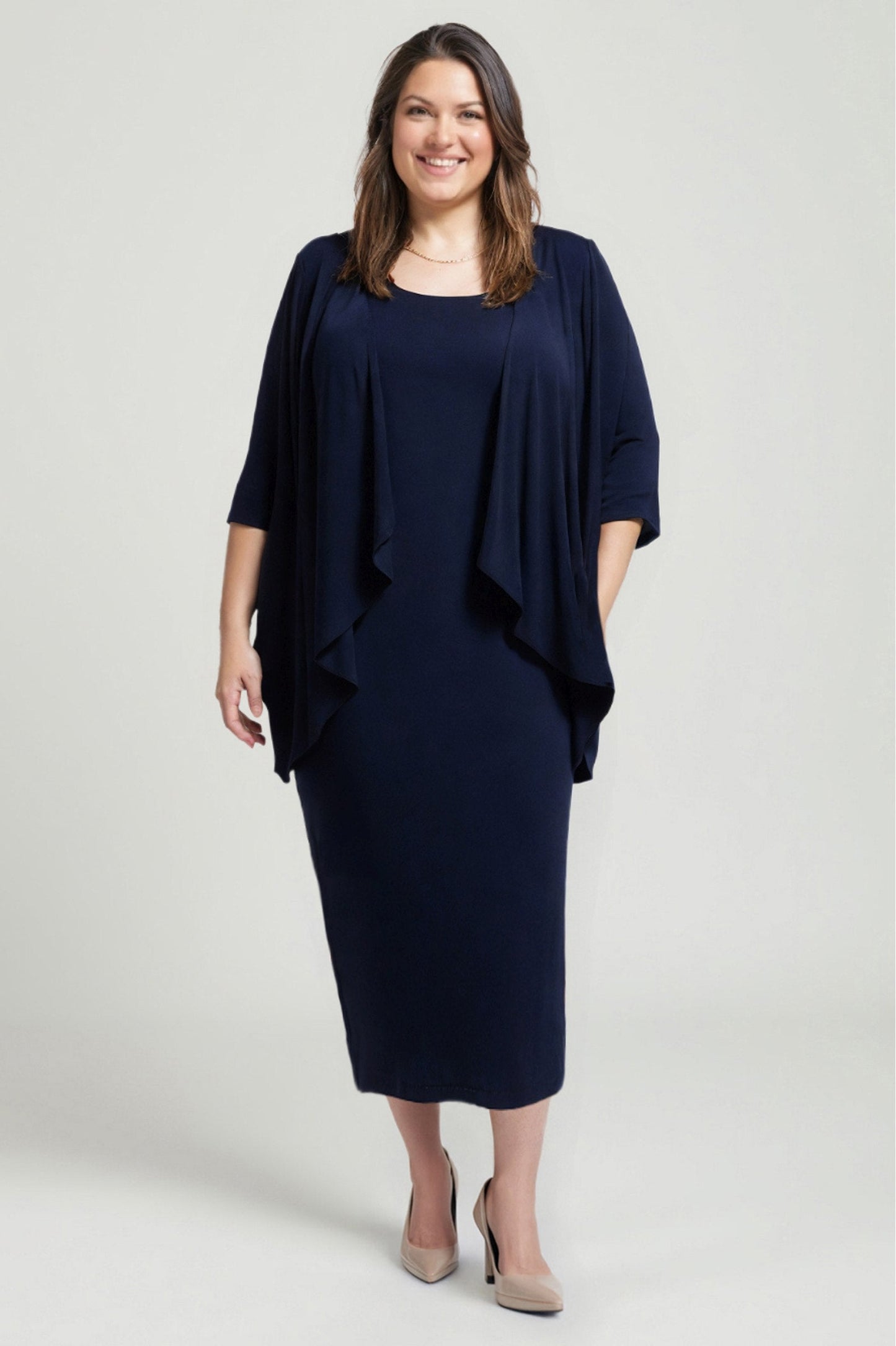 Woman wearing a navy blue dress with a draped effect on a light gray background