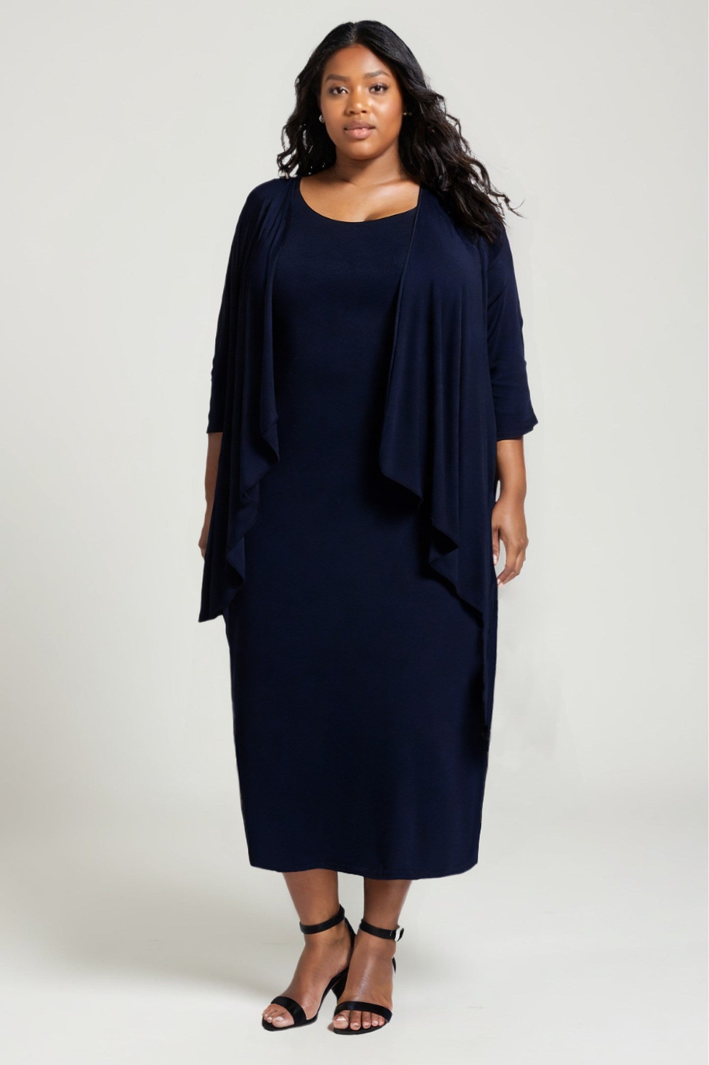 Woman wearing a navy blue dress with a matching jacket on a white background