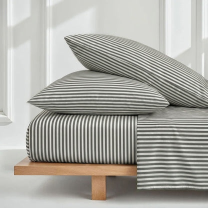 Striped bedding set on a wooden bed frame with white walls and windows in the background