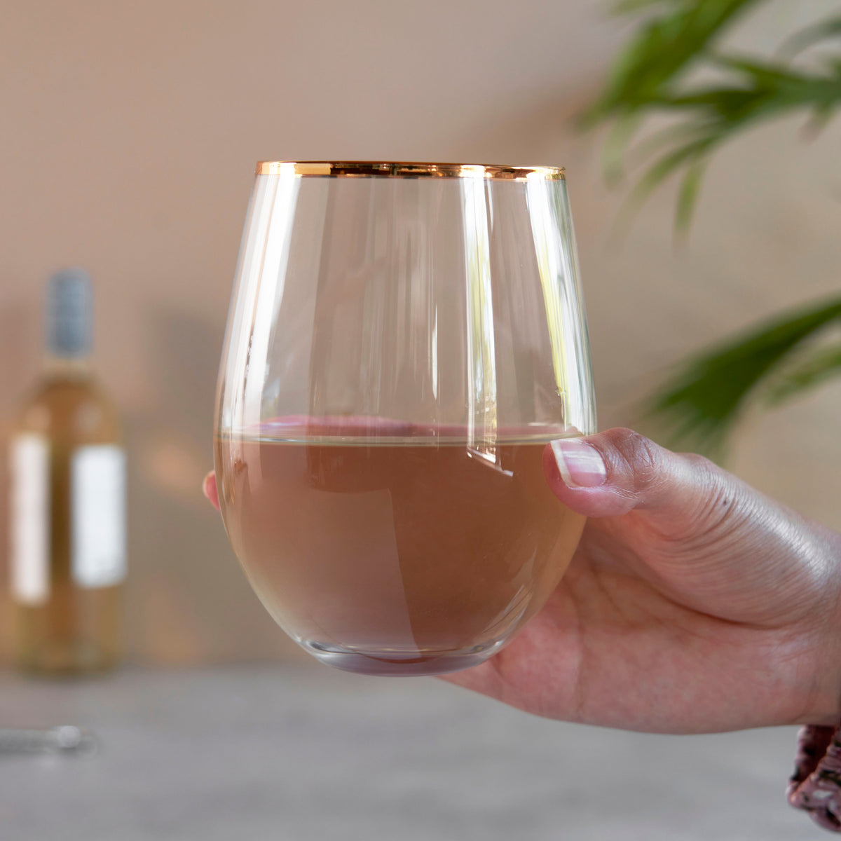 Hand holding a glass of pink wine with a blurred background