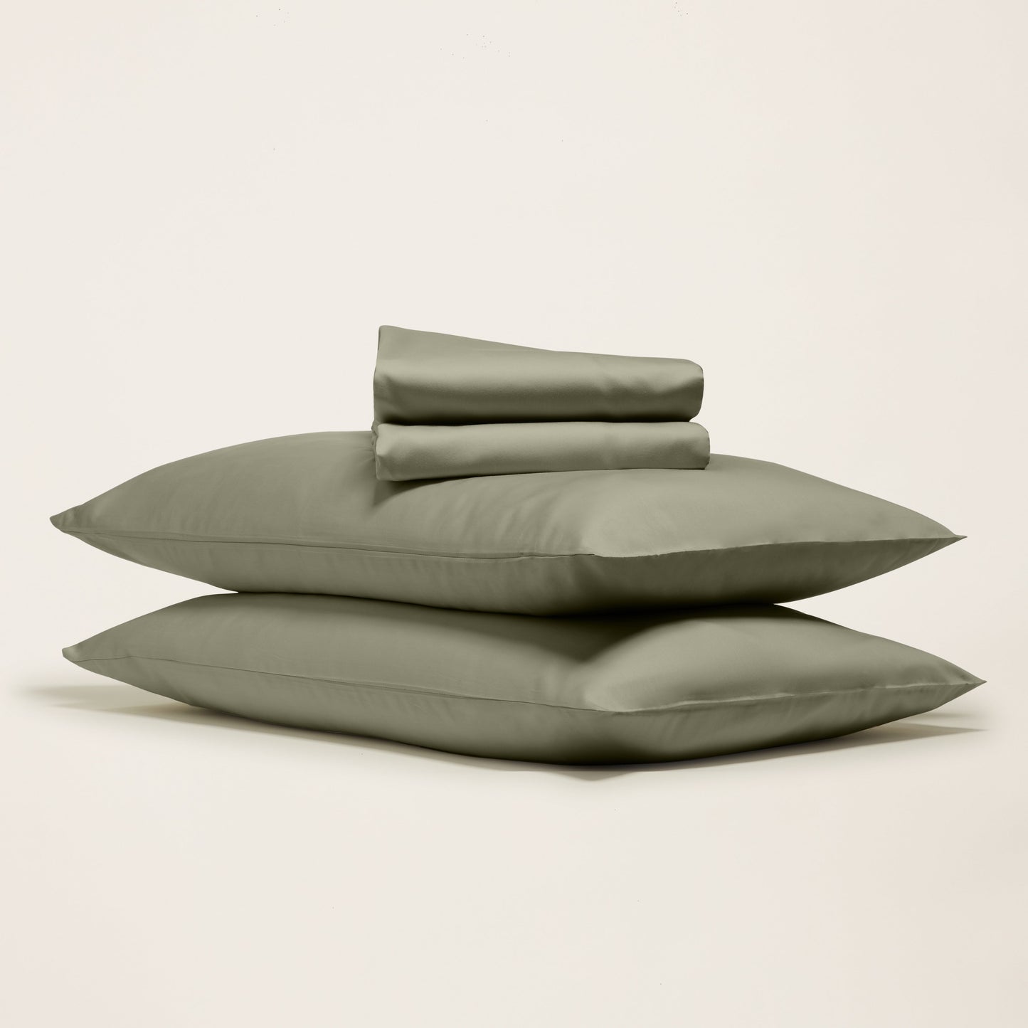 Set of green bedding including two pillows and a duvet cover on a light beige background