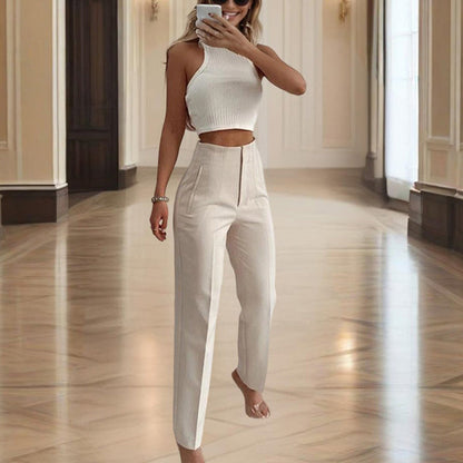 Woman in a white outfit taking a mirror selfie in a well-lit room.