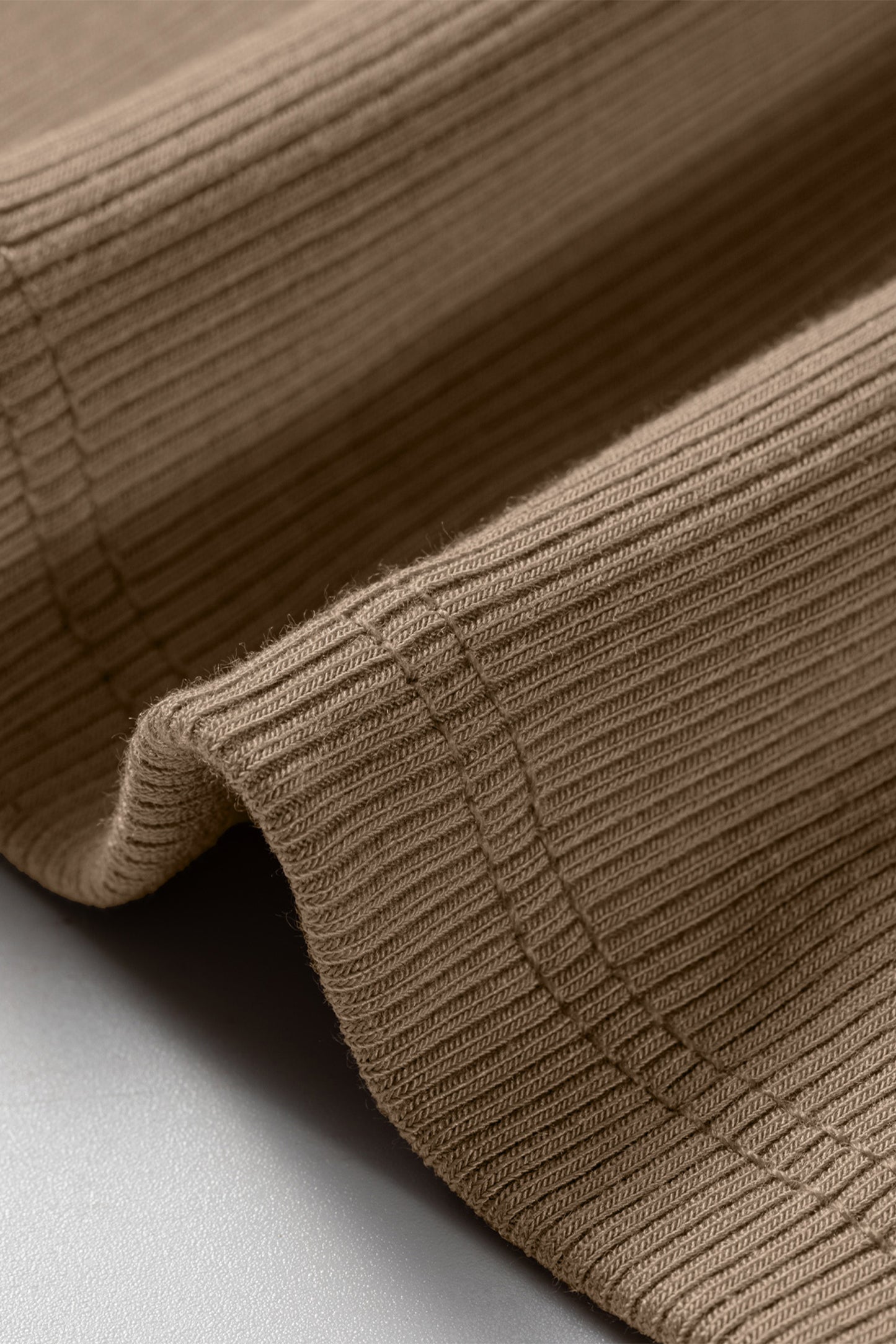 Close-up of a brown ribbed fabric tank top showing vertical texture and double-stitched seams.