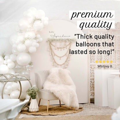 Decorative setup with white balloons, chair, and macrame wall hanging in a room.