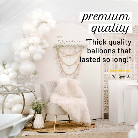 Decorative setup with white balloons, chair, and macrame wall hanging in a room.