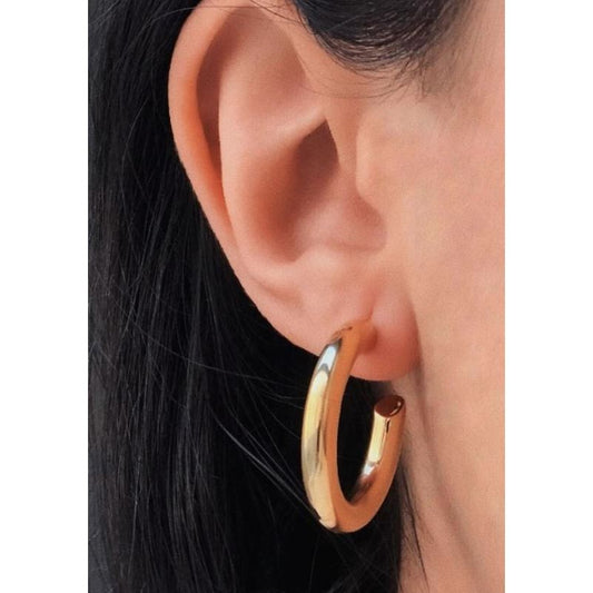Gold hoop earring worn by a person with dark hair.