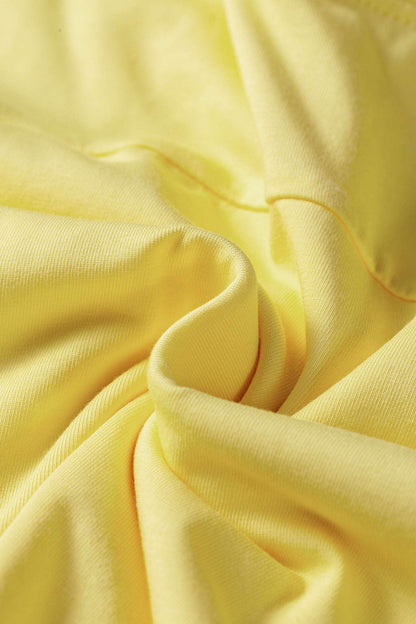 A close-up of draped light yellow fabric with soft folds and a smooth texture.