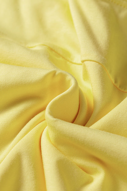 A close-up of draped light yellow fabric with soft folds and a smooth texture.