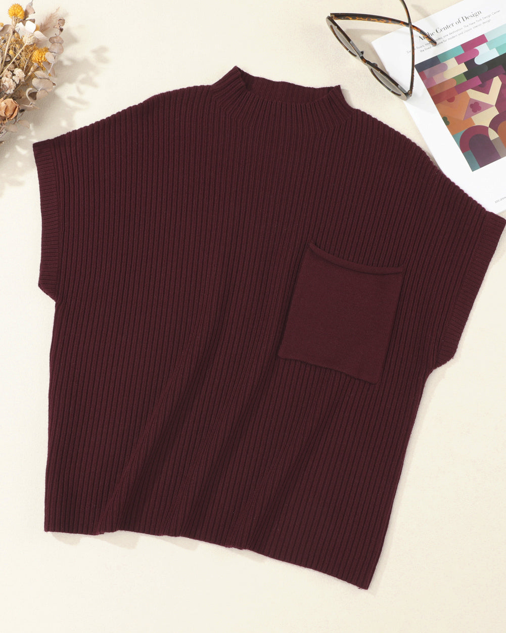Brown ribbed sweater vest on a light surface with decorative items.