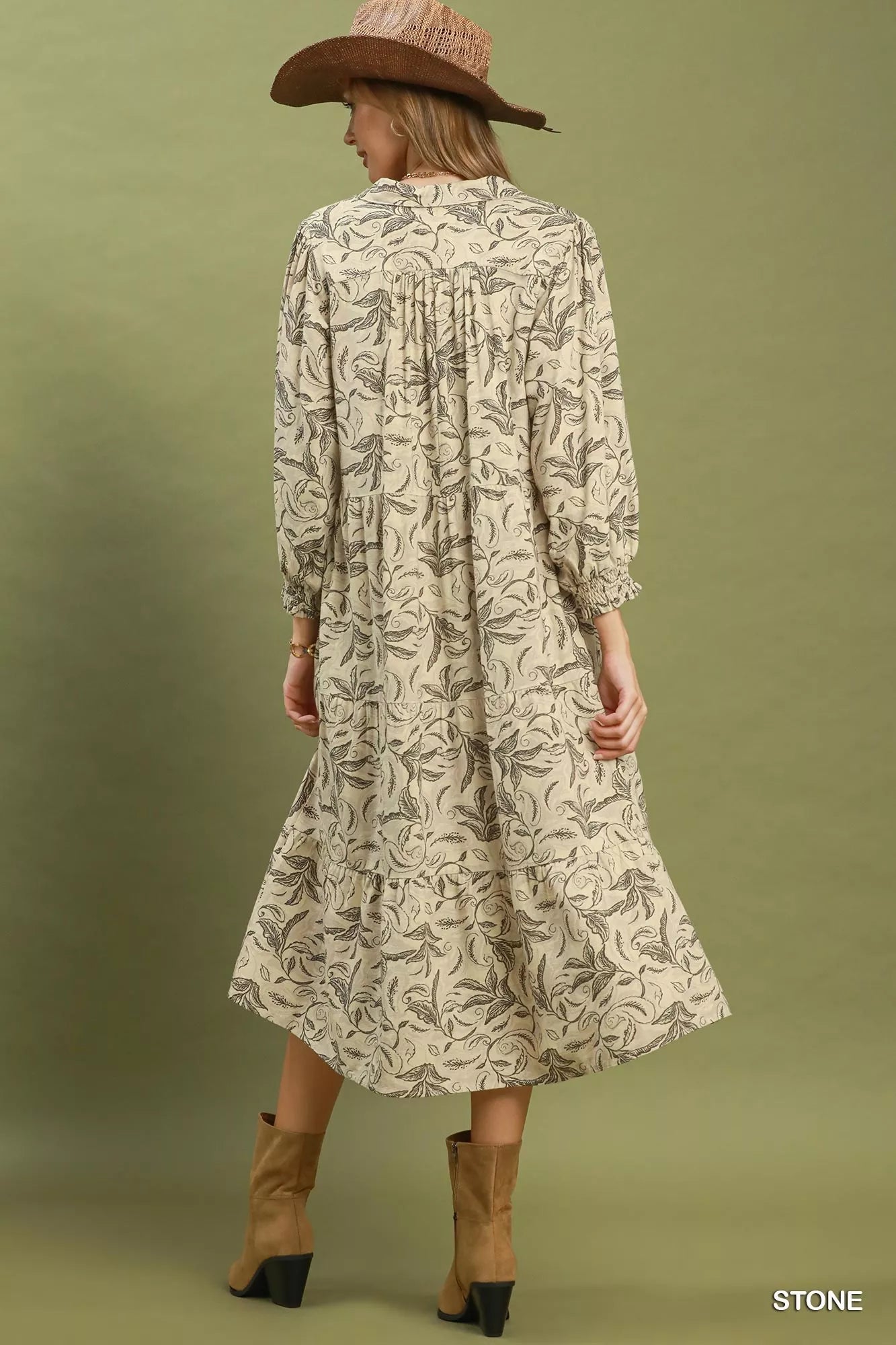 Woman wearing a patterned dress and hat on an olive green background