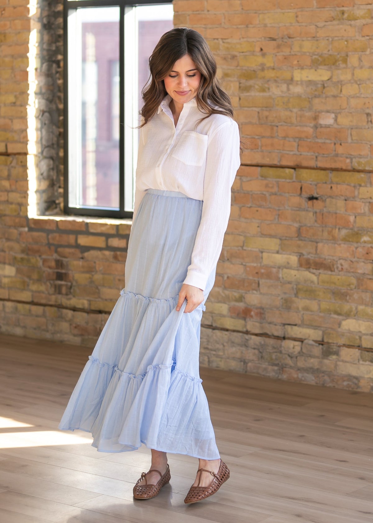 Woman wearing the Bailey crisp white cotton gauze button down top with a denim maxi skirt