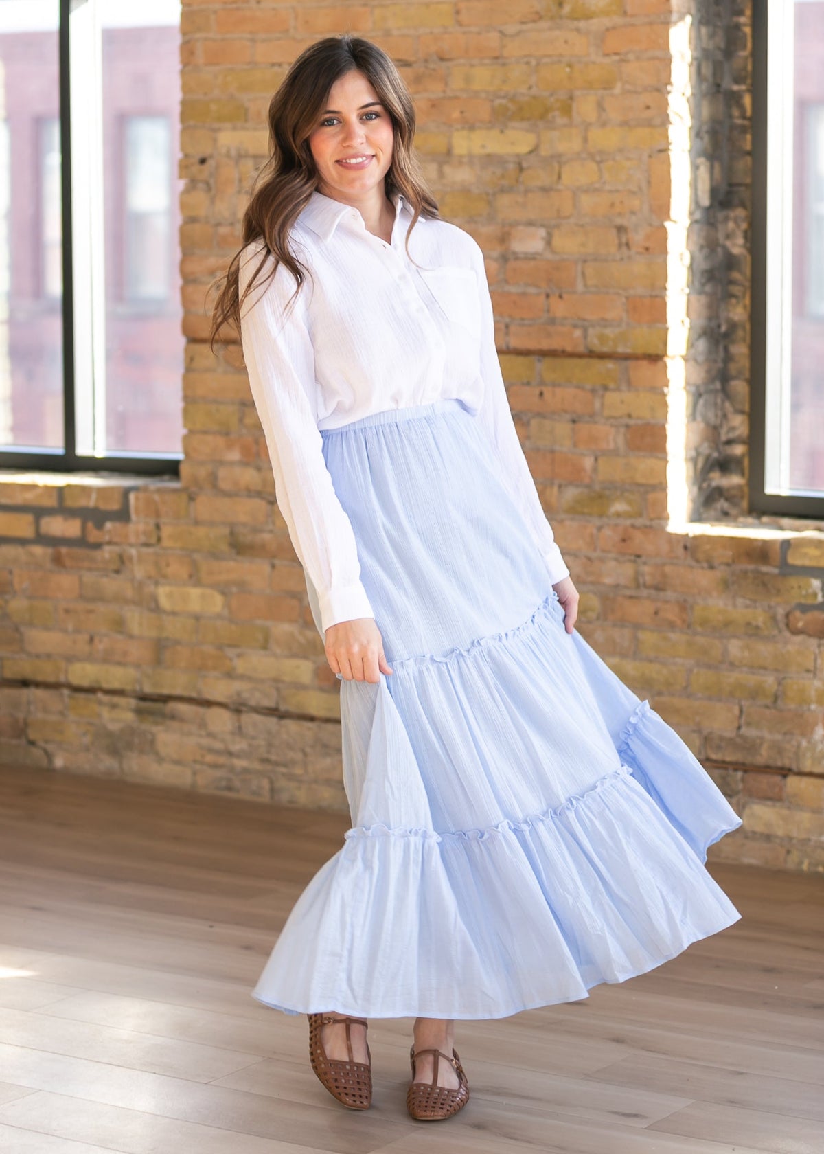 Woman wearing the Bailey crisp white cotton gauze button down top with a denim maxi skirt