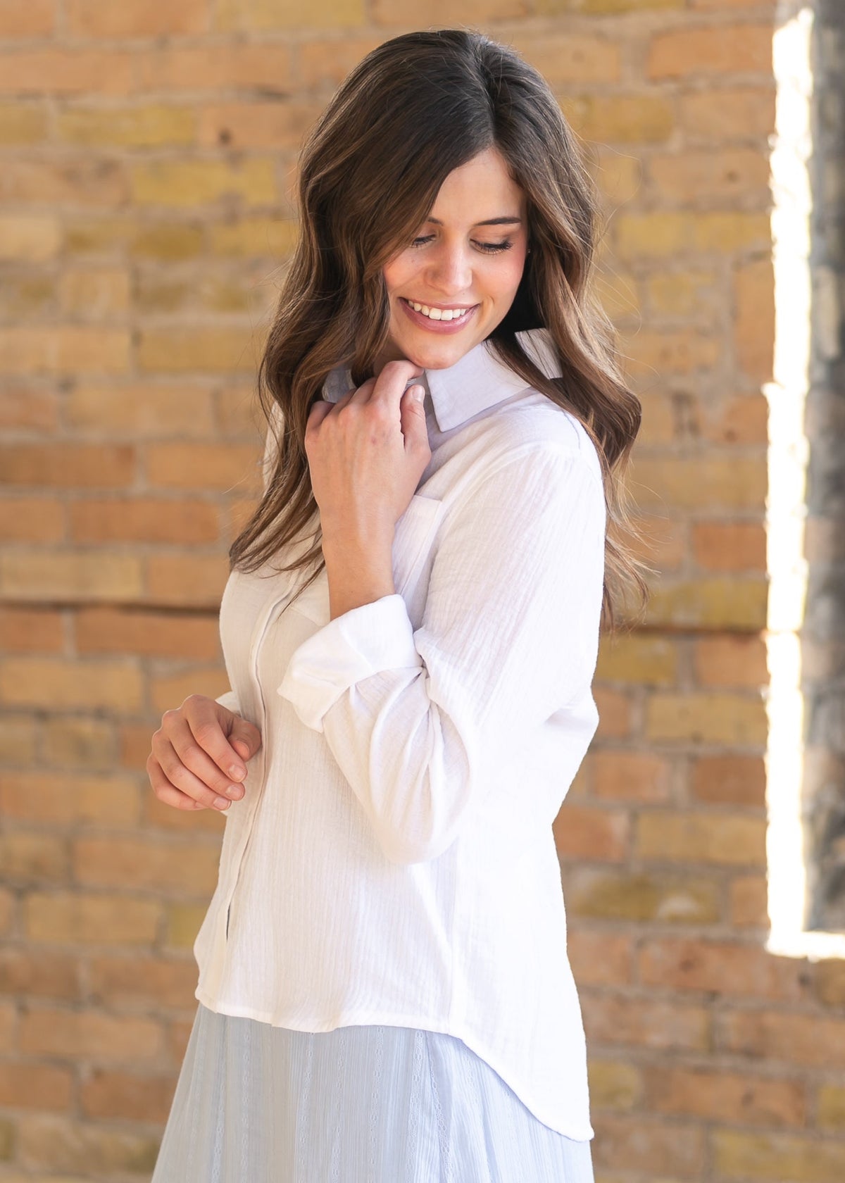 Woman wearing the Bailey crisp white cotton gauze button down top with a denim maxi skirt