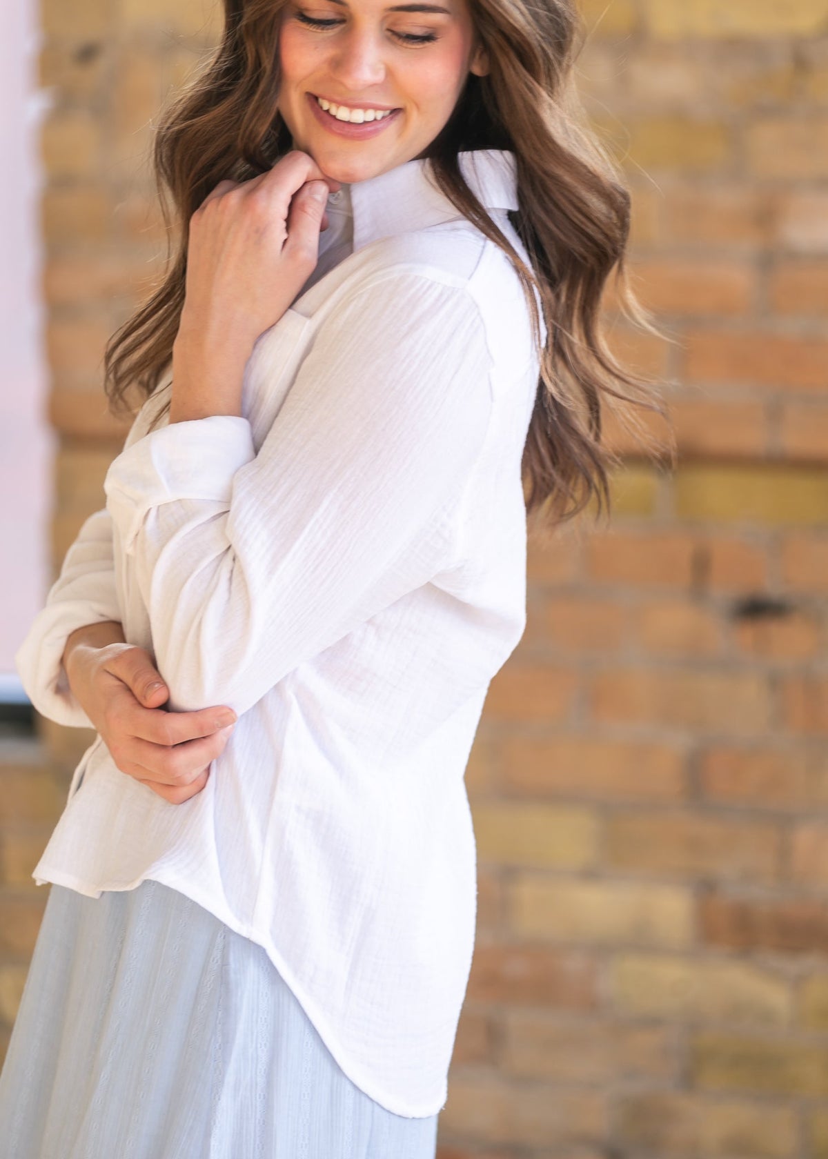 Woman wearing the Bailey crisp white cotton gauze button down top with a denim maxi skirt