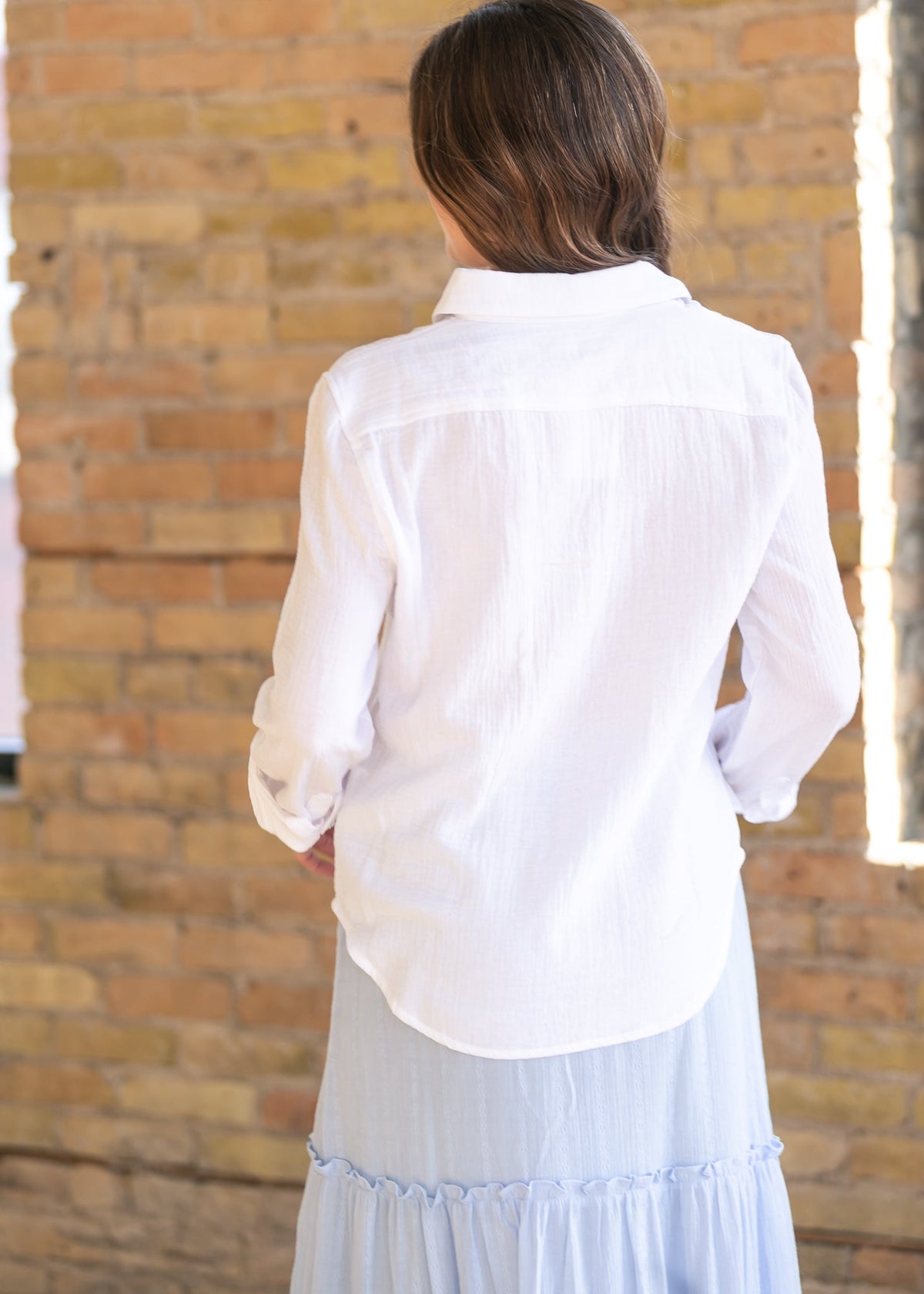 Woman wearing the Bailey crisp white cotton gauze button down top with a denim maxi skirt