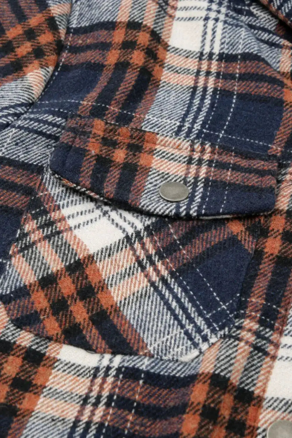 Close-up of a plaid fabric with orange, blue, and white colors.