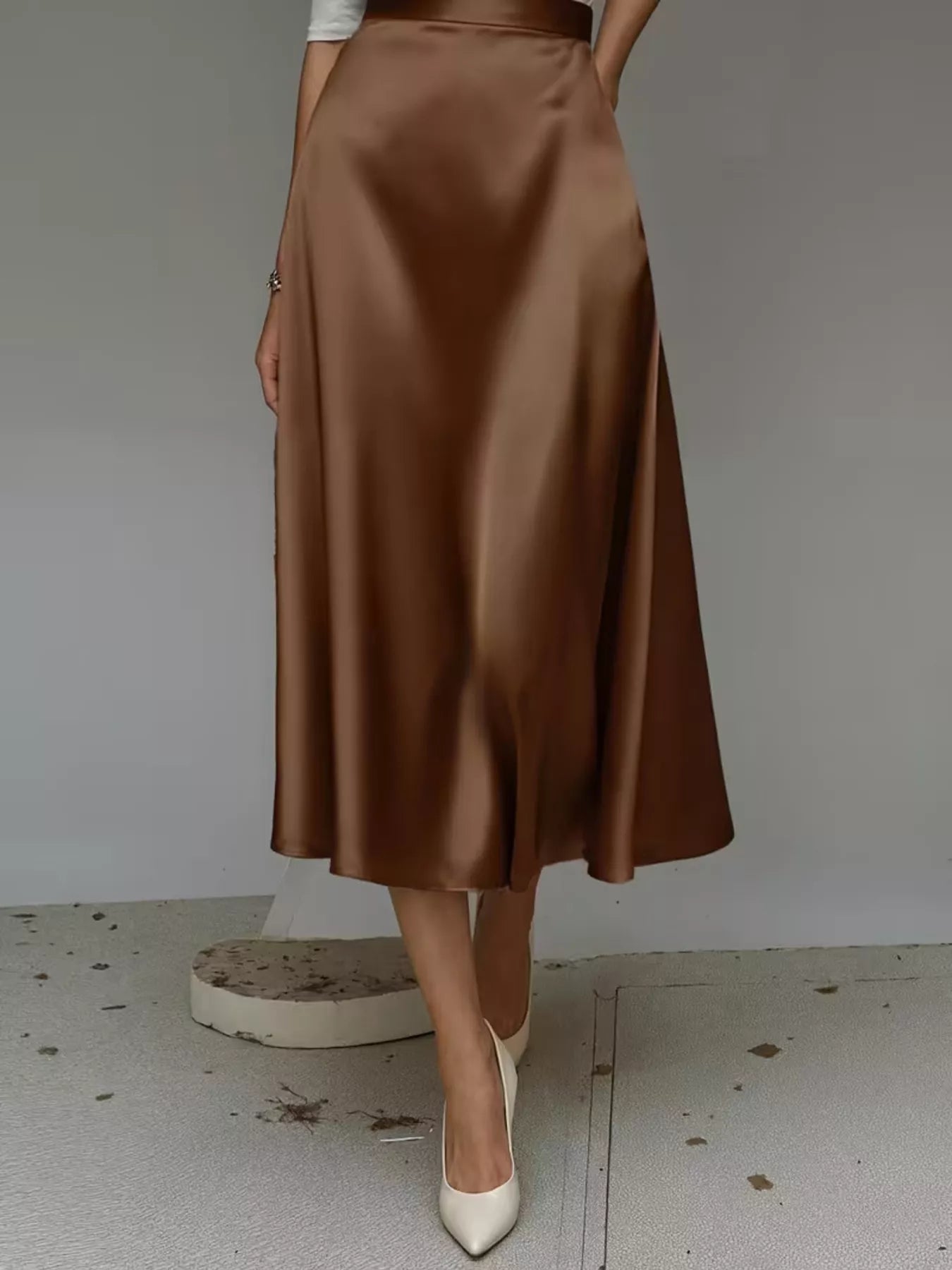 Brown satin skirt worn by a person on a plain background