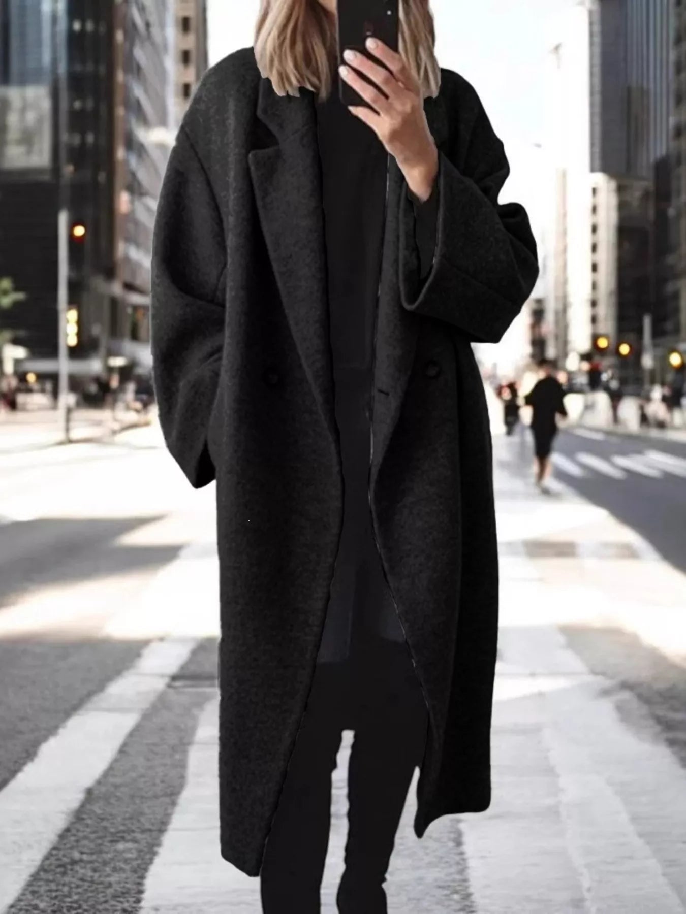 Person wearing a long black coat on a city street