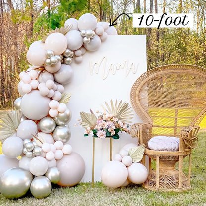 Balloon arch with '10-foot' text, wicker chair, and floral arrangement outdoors.