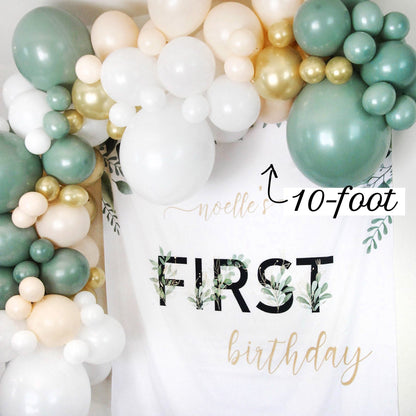 Balloon arch with 'noelle's 10-foot FIRST birthday' text on a white background