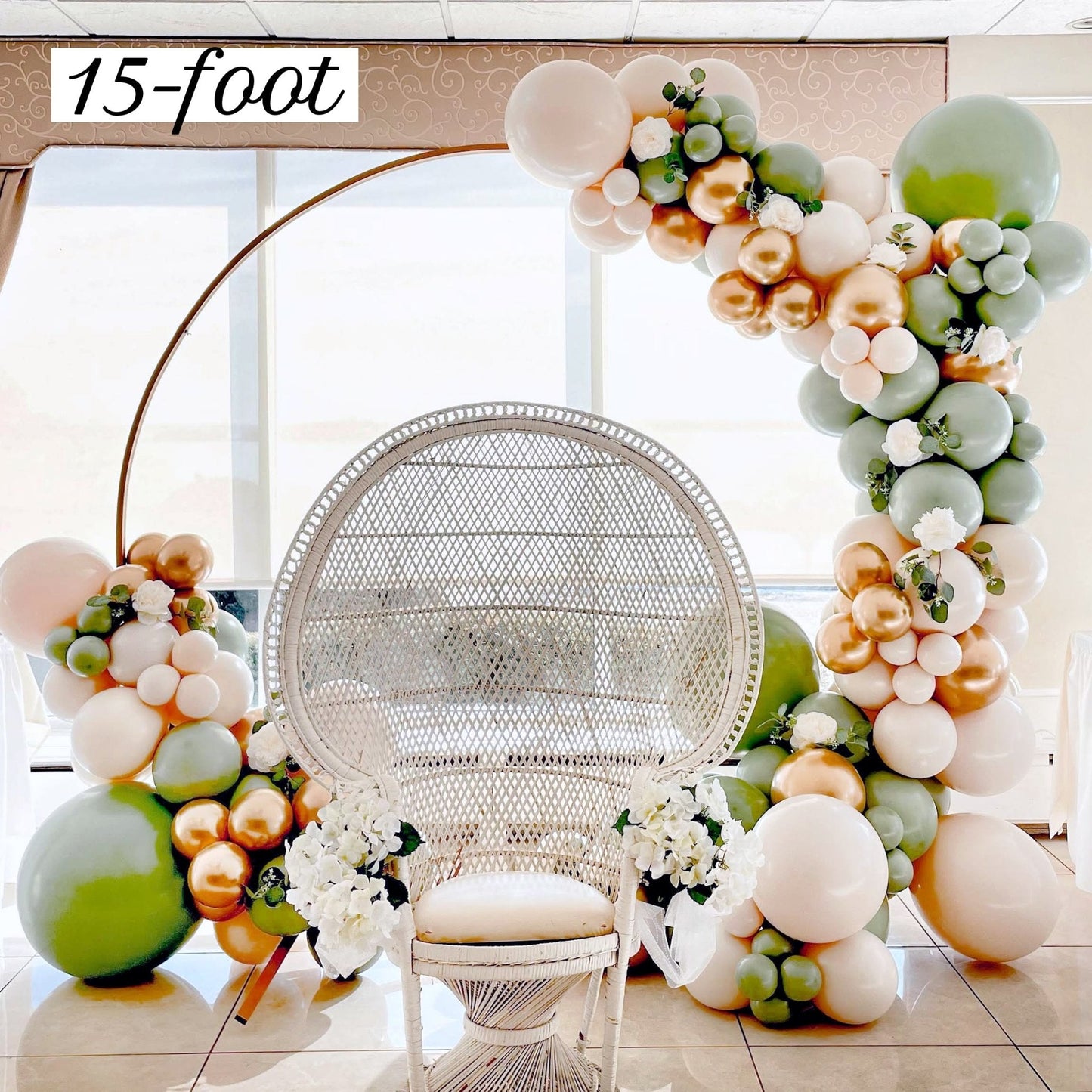 Balloon arch with flowers and a wicker chair in a room.