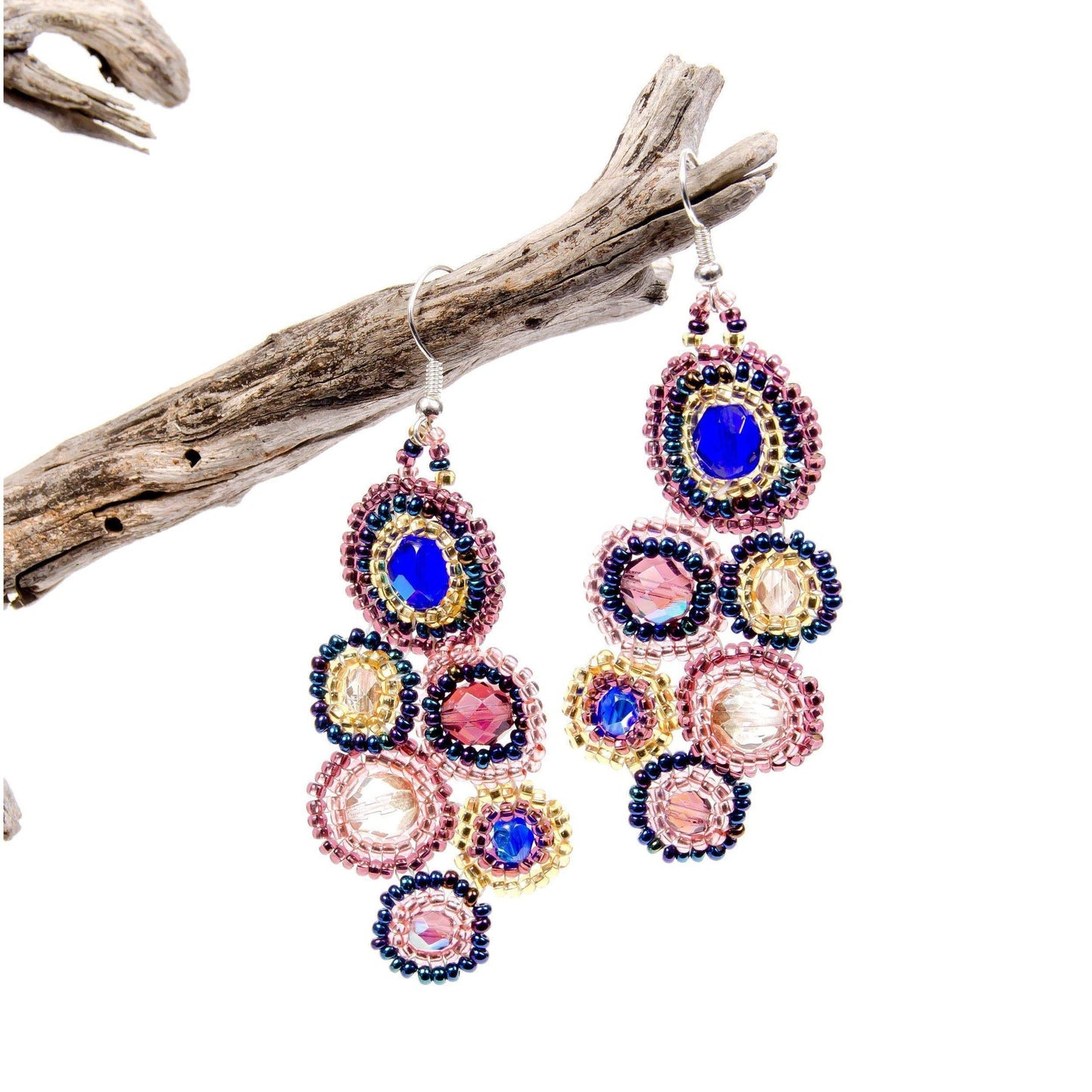 Colorful beaded earrings on a white background with a piece of driftwood.