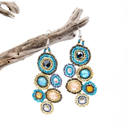 Colorful beaded earrings on a white background with a branch.