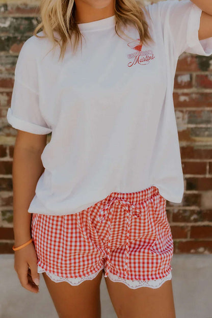 Red and white gingham shorts with a tie waist and white lace hem, paired with a white Espresso Martini t-shirt.