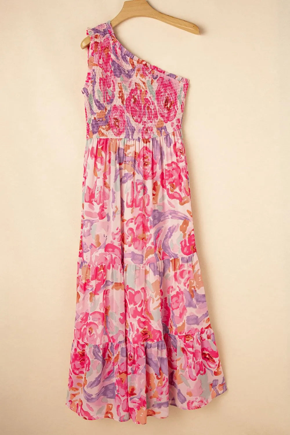 Floral dress hanging on a wooden hanger against a beige background